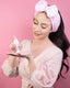 Woman in pampering attire spraying foam into hand. Woman and product shot in pink setting background.